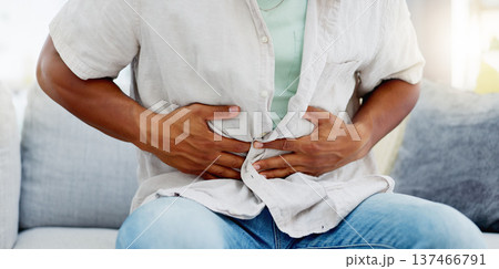 Man on a sofa with a tummy ache, pain or sickness while relaxing in the living room of his home. Illness, medical emergency and male with diarrhea, food poisoning or indigestion rubbing his stomach. Man on a sofa with a tummy ache, pain or sickness while relaxing in the living room of his home. Illness, medical emergency and male with diarrhea, food poisoning or indigestion rubbing his stomach. 137466791