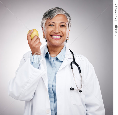 Doctor, woman and portrait with apple in studio for vitamin c benefits, detox and dietician on gray background. Happy mature nutritionist with fresh fruits for nutrition, healthy food and wellness Doctor, woman and portrait with apple in studio for vitamin c benefits, detox and dietician on gray background. Happy mature nutritionist with fresh fruits for nutrition, healthy food and wellness 137466937