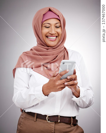 Smile, phone and mature muslim woman in a studio scroll on social media, mobile app or the internet. Happy, religion and islamic female model with a hijab browsing on a cellphone by a gray background Smile, phone and mature muslim woman in a studio scroll on social media, mobile app or the internet. Happy, religion and islamic female model with a hijab browsing on a cellphone by a gray background 137467000