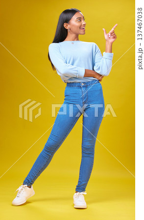 Pointing, marketing and young woman in a studio for advertising, creative or promotion. Smile, happy and full length of Indian female model with a direction hand gesture isolated by yellow background 137467038