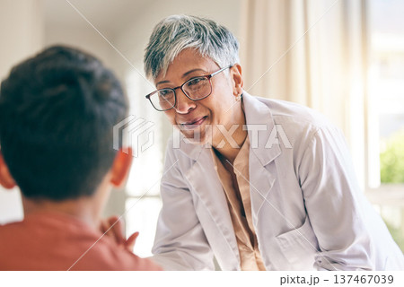 Mature doctor, smile and woman with child in consultation at hospital, healthcare and wellness. Pediatrician, happy and medical professional with kid in communication, help patient or check at clinic 137467039