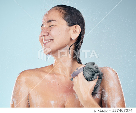 Clean, woman and shower with water, soap and sponge for healthy dermatology, skincare and blue background in studio. Person, smile and washing skin and body with foam bubbles in bathroom Clean, woman and shower with water, soap and sponge for healthy dermatology, skincare and blue background in studio. Person, smile and washing skin and body with foam bubbles in bathroom 137467074
