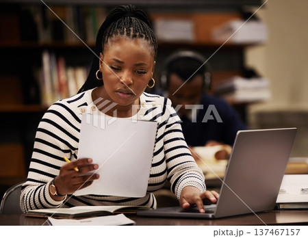 Student, woman and documents on laptop in library for study, research and planning in university. Young african person with paper and computer for reading or focus in English, education or philosophy 137467157