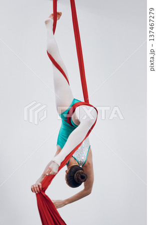 Performance, acrobat and aerial silk with a woman in air for gymnastics, sports and balance. Athlete person, dancer or gymnast hanging on red fabric and white background with space, art or creativity Performance, acrobat and aerial silk with a woman in air for gymnastics, sports and balance. Athlete person, dancer or gymnast hanging on red fabric and white background with space, art or creativity 137467279