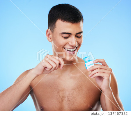 Dental floss, man and teeth cleaning for healthcare, wellness and morning care in studio. Blue background, male model and happy from mouth hygiene with smile from healthy product for tooth protection 137467582