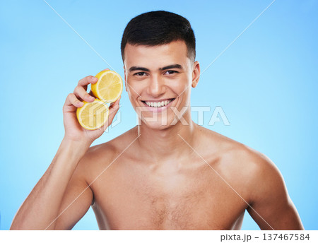 Beauty, health and portrait of man and lemon in studio for health, detox and natural cosmetics. Vitamin c, nutrition and skincare with person and fruit on blue background for self care, spa and glow 137467584