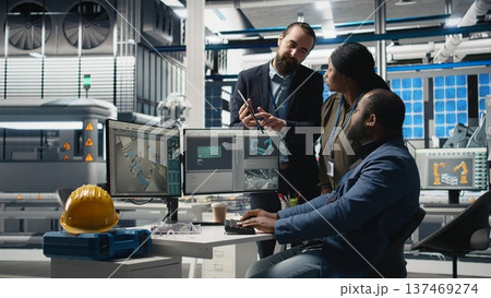 Multiethnic team of experts collaborating in a solar panel power plant, reviewing blueprints and production line metrics to ensure clean energy manufacturing and sustainability. Camera A. Multiethnic team of experts collaborating in a solar panel power plant, reviewing blueprints and production line metrics to ensure clean energy manufacturing and sustainability. Camera A. 137469274