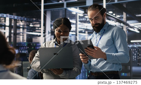 Data scientists working together in server room, reviewing neural network code and LLM visualization dashboards. Team of IT experts coordinating tasks, monitoring AI system performance, camera A Data scientists working together in server room, reviewing neural network code and LLM visualization dashboards. Team of IT experts coordinating tasks, monitoring AI system performance, camera A 137469275