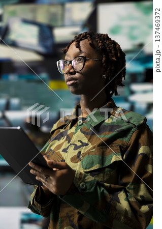African american army soldier using device app to track hostile threats. Communications expert in base of operations using target acquisition tech on tablet to detect enemy location 137469372