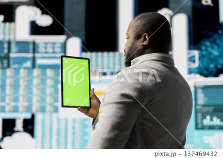 Young african american leader reviewing mockup screen with data insight for business development, surrounded by fintech charts and KPI projections. Financial performance and decision making. Young african american leader reviewing mockup screen with data insight for business development, surrounded by fintech charts and KPI projections. Financial performance and decision making. 137469432