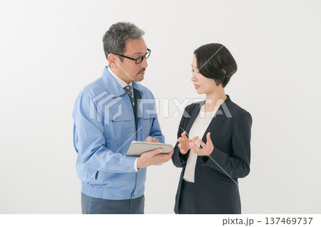 打ち合わせをする作業服の男性とスーツの女性 打ち合わせをする作業服の男性とスーツの女性 137469737