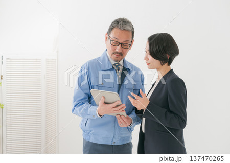 打ち合わせをする作業服の男性とスーツの女性 137470265