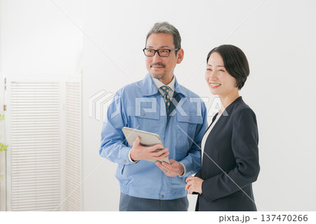 打ち合わせをする作業服の男性とスーツの女性 打ち合わせをする作業服の男性とスーツの女性 137470266