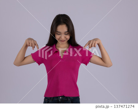 Woman in pink shirt pointing fingers down at floor 137471274