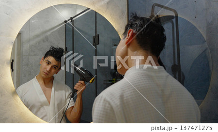 Person blow drying their hair in front of a mirror 137471275