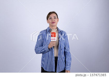 Female reporter in denim shirt talking into microphone 137471365