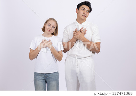 Young couple in white t-shirts making heart shape with hands Young couple in white t-shirts making heart shape with hands 137471369