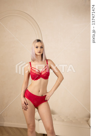 Young woman in red lingerie posing against a wall Young woman in red lingerie posing against a wall 137471474