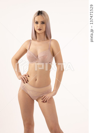 Young woman in beige lingerie posing against a wall Young woman in beige lingerie posing against a wall 137471529