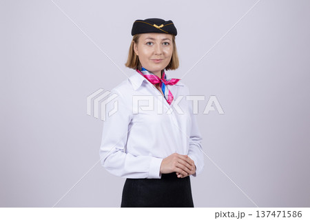 Woman flight attendant in uniform and hat looking at camera Woman flight attendant in uniform and hat looking at camera 137471586