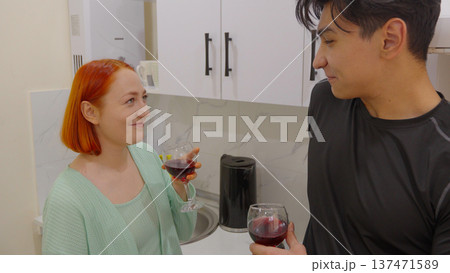 Young couple talking and drinking wine in the kitchen 137471589