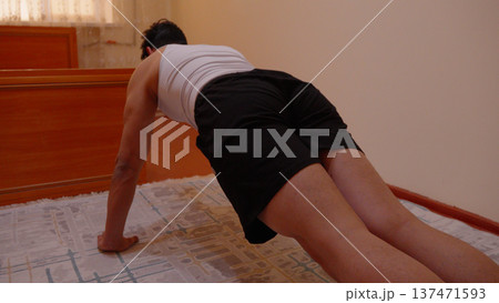 Athletic young man doing push ups on the floor in a room Athletic young man doing push ups on the floor in a room 137471593