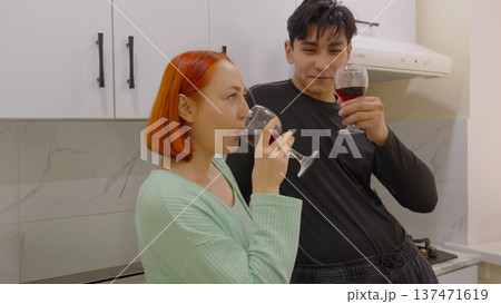 Young couple drinking wine together in a modern kitchen Young couple drinking wine together in a modern kitchen 137471619