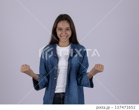 Excited young woman in denim shirt showing victory gesture Excited young woman in denim shirt showing victory gesture 137471652