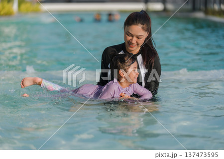 preschool child girl playing and swimming with her mother in pool preschool child girl playing and swimming with her mother in pool 137473595
