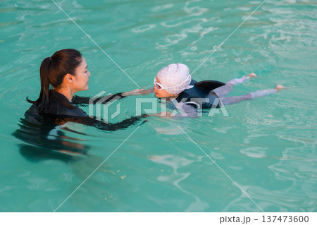 preschool child girl in life jacket learning to swim with mother in swimming pool 137473600