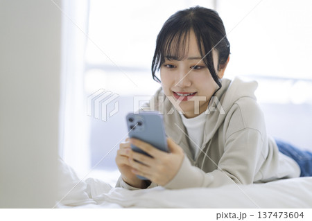 スマートフォンの画面を見ながら微笑む若い女性 137473604