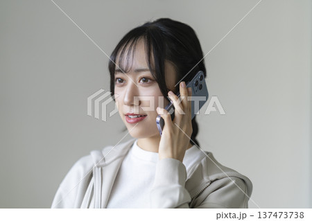 スマートフォンで通話する笑顔の若い女性 スマートフォンで通話する笑顔の若い女性 137473738