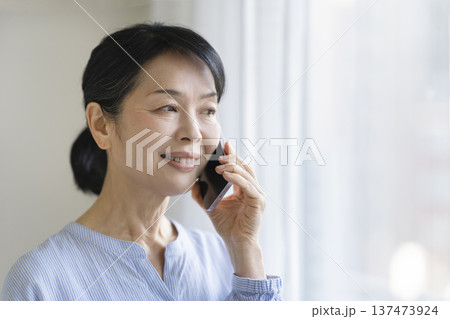 スマートフォンで通話する笑顔の50代後半の女性 137473924