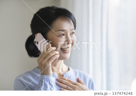 スマートフォンで通話する笑顔の50代後半の女性 スマートフォンで通話する笑顔の50代後半の女性 137474248