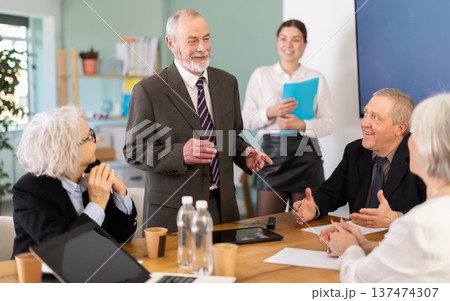 Senior male speaker shares happy news, makes participants laugh 137474307