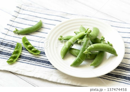 白皿に乗せたスナップエンドウと割ったさや 137474458