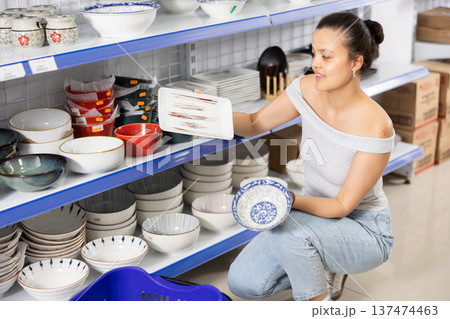 Woman looking for new plates at store of household goods 137474463