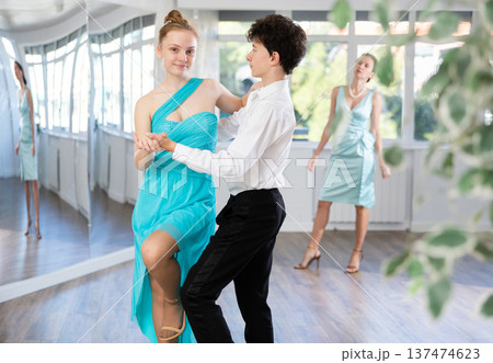 Pair dances - girl and boy in festive attire dance waltz in studio Pair dances - girl and boy in festive attire dance waltz in studio 137474623