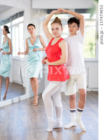 Experienced dance teacher teaching ballroom dancing to a couple of teenagers in studio 137474652