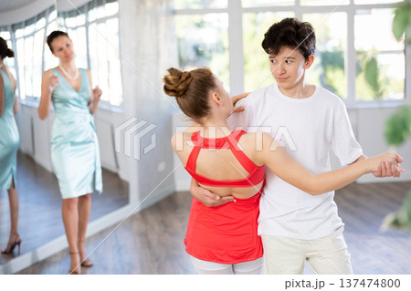 Teenage girl and boy practicing waltz in dance hall with female mentor Teenage girl and boy practicing waltz in dance hall with female mentor 137474800