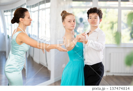 Female dance teacher fine-tuning positions of teenage students during dance class Female dance teacher fine-tuning positions of teenage students during dance class 137474814
