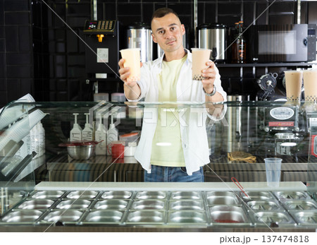 Happy man with two glasses of bubble tea in the grocery department of supermarket Happy man with two glasses of bubble tea in the grocery department of supermarket 137474818