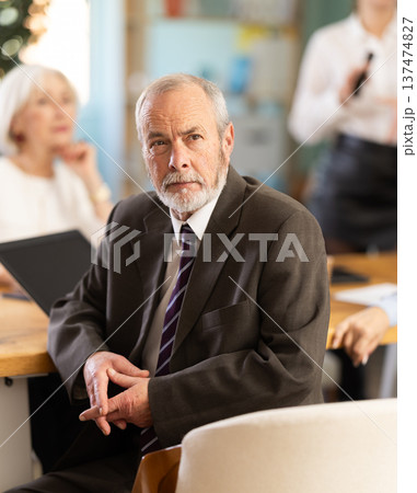 Elderly man in group watches presentation given by young secretary Elderly man in group watches presentation given by young secretary 137474827