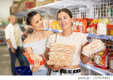 Woman invites her friend to buy traditional Chinese noodles at grocery store. 137474887