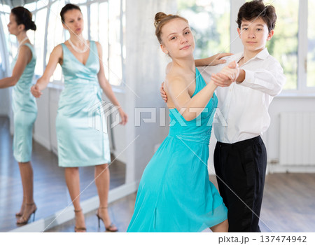 Girl and a boy in festive clothes learn to dance tango under guidance of teacher Girl and a boy in festive clothes learn to dance tango under guidance of teacher 137474942