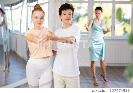 Teenage girl and boy practicing waltz in dance hall with female mentor Teenage girl and boy practicing waltz in dance hall with female mentor 137474988