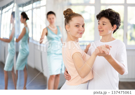 Couple of teenage dancers rehearsing ballroom dance with female teacher Couple of teenage dancers rehearsing ballroom dance with female teacher 137475061