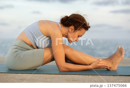 Warm-up and stretching of the body before yoga classes on ocean shore Warm-up and stretching of the body before yoga classes on ocean shore 137475066