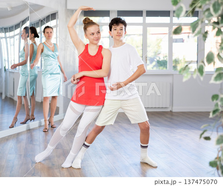 Young happy couple performing paired dance in ballroom. Dance teacher watches closely 137475070
