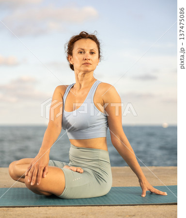 Yoga practice on embankment, female athlete fulfil carry out padmasana svastikasana, Siddhasana 137475086